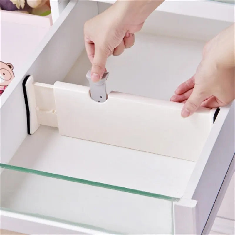 Adjustable white plastic drawer divider being installed inside a drawer.