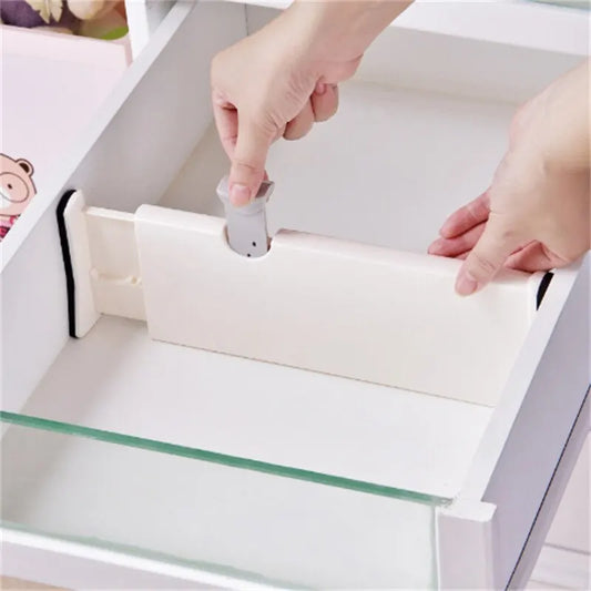 Adjustable white plastic drawer divider being installed inside a drawer.